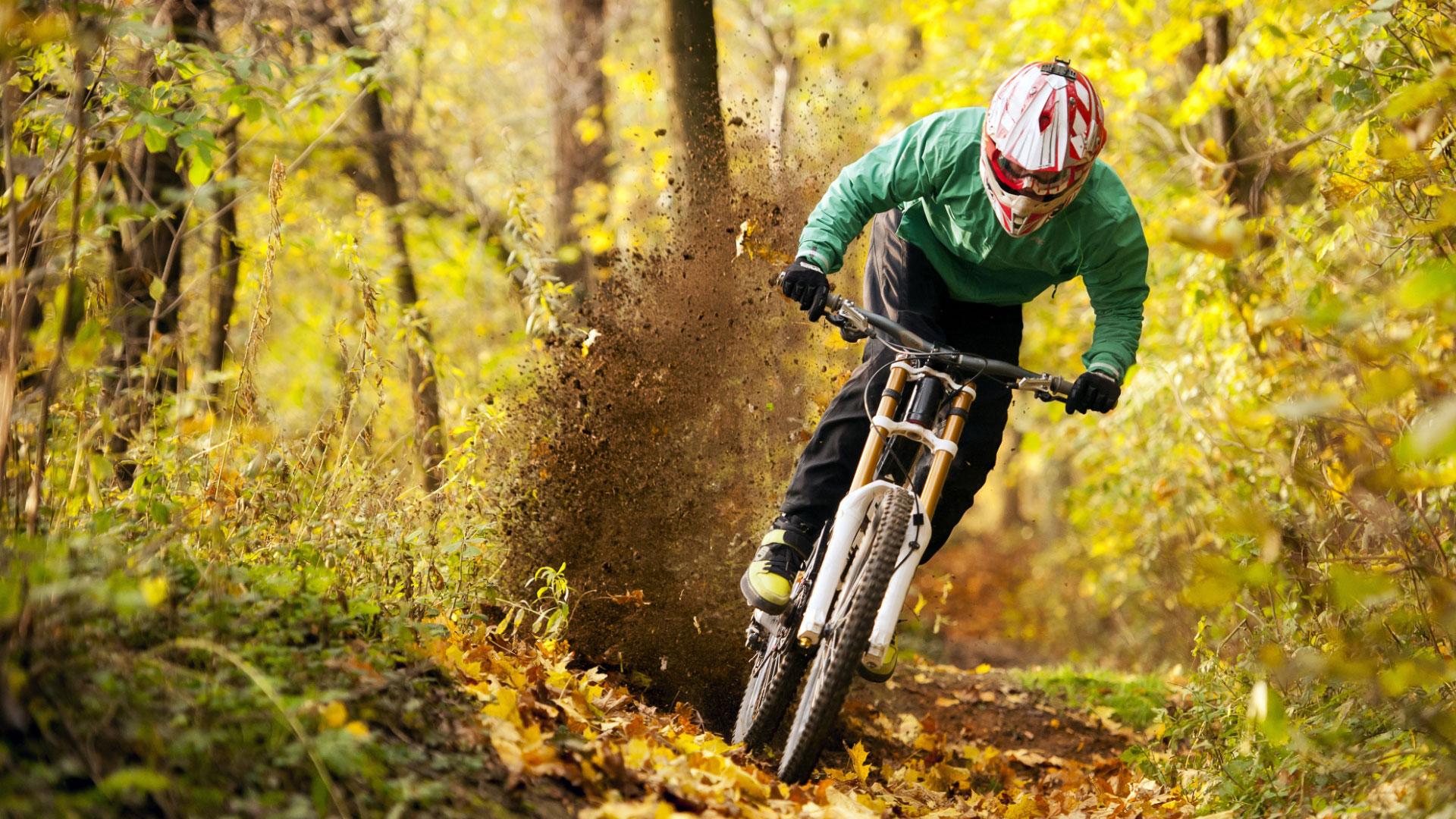 Cyclist on autumn forest trail, kicking up dirt with the bike.