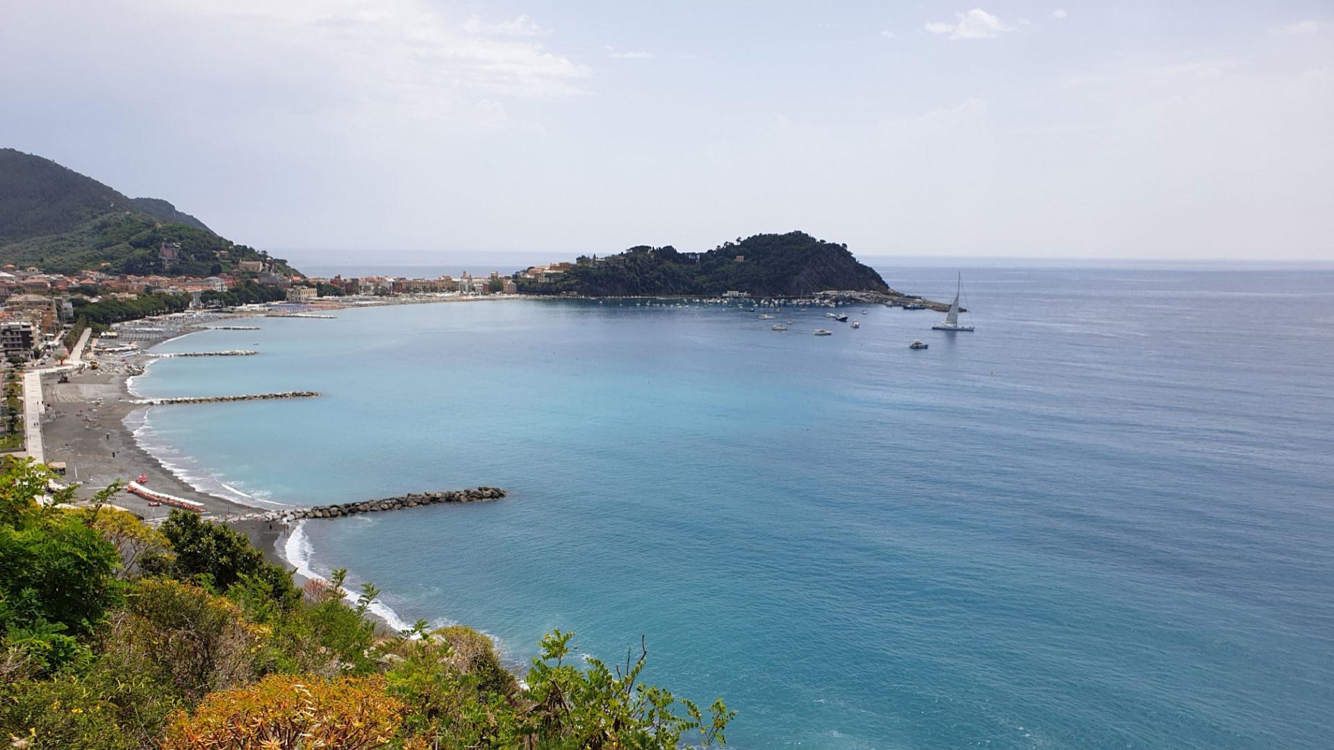 Vista panoramica di una baia con spiaggia, mare azzurro e barche ormeggiate.