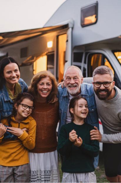 Happy family camping in front of a modern RV.