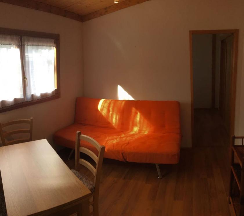 Living room with orange sofa, table and chairs near window.