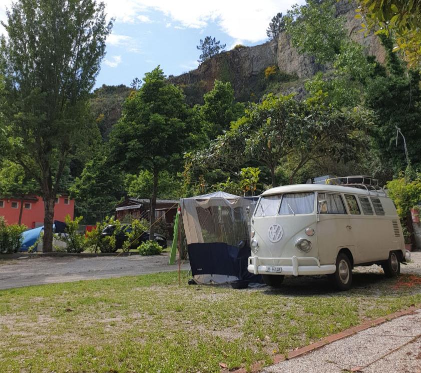 Classic Volkswagen van parked at a green campsite with a cliff view.