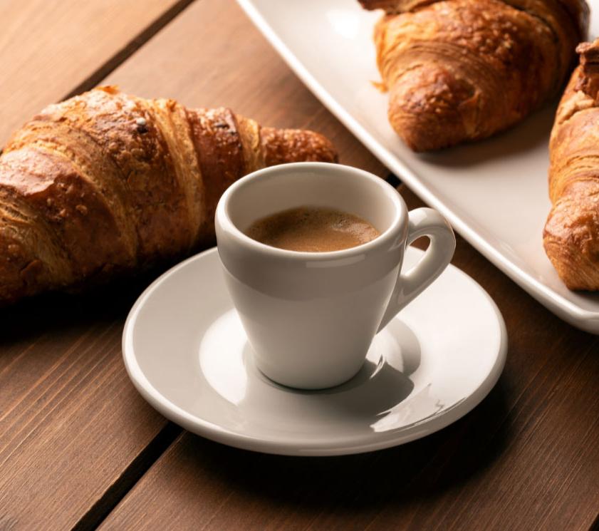 Colazione con croissant e caffè su tavolo in legno.